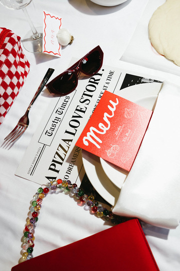 Table detail: newspaper, menu, sunglasses and beaded necklace