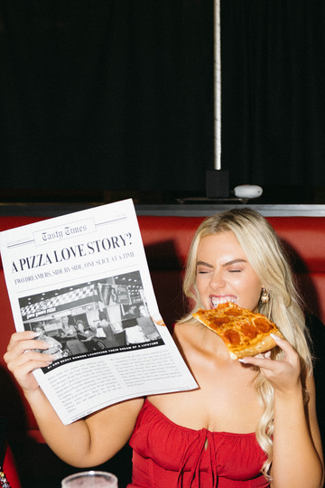 A guest in red with a slice and the custom newspaper