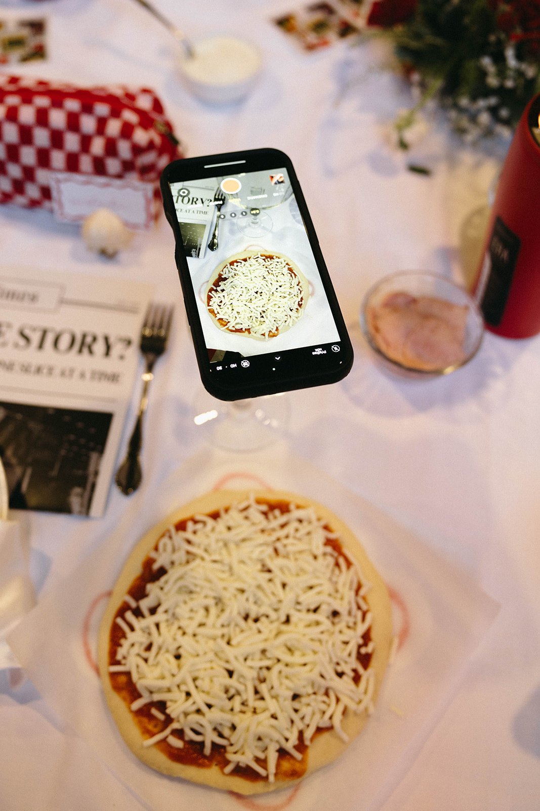 A guest photographs her handmade take-home pizza at the table