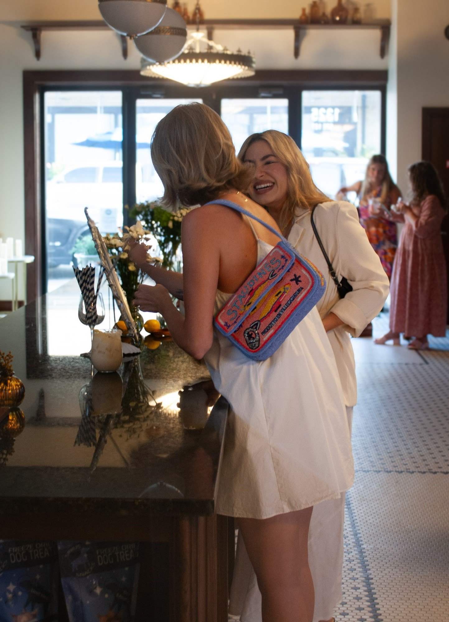 Two guests greet each other with a hug at the bar