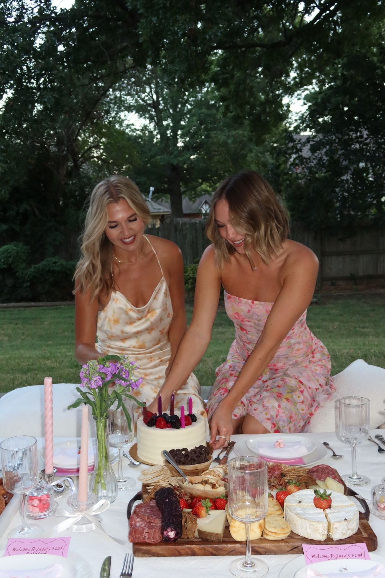 The birthday girl and a friend light the berry-topped cake