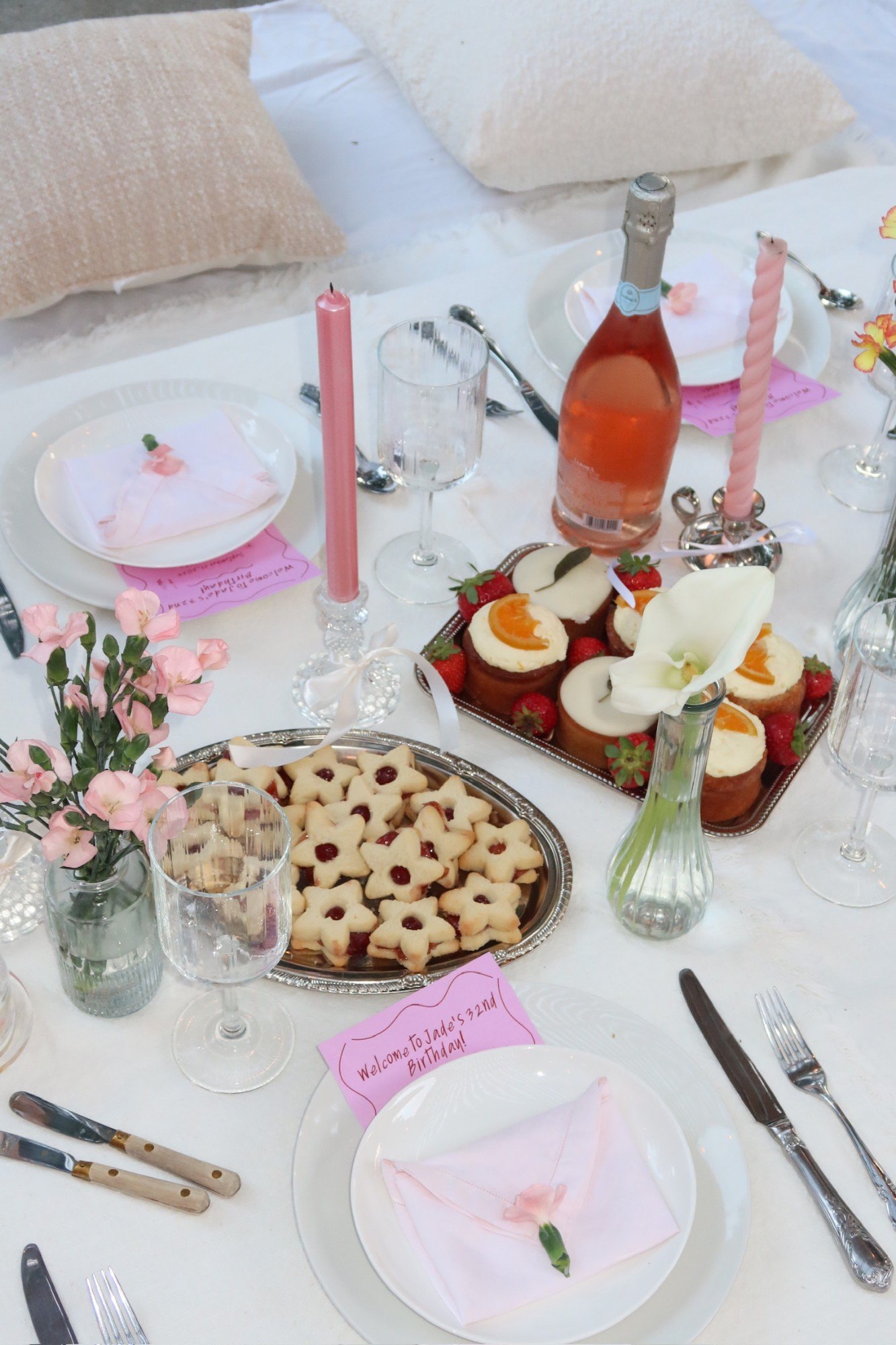 Rosé, mini cakes and star cookies on silver trays with pink tapers