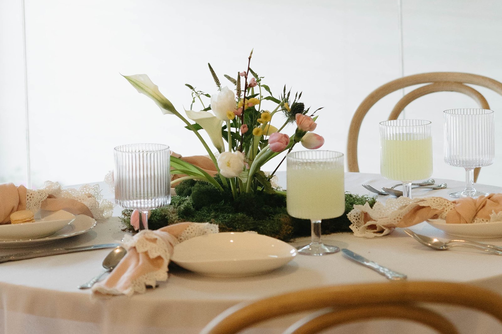 Tulips and calla lilies rising from the moss beside glasses of limeade