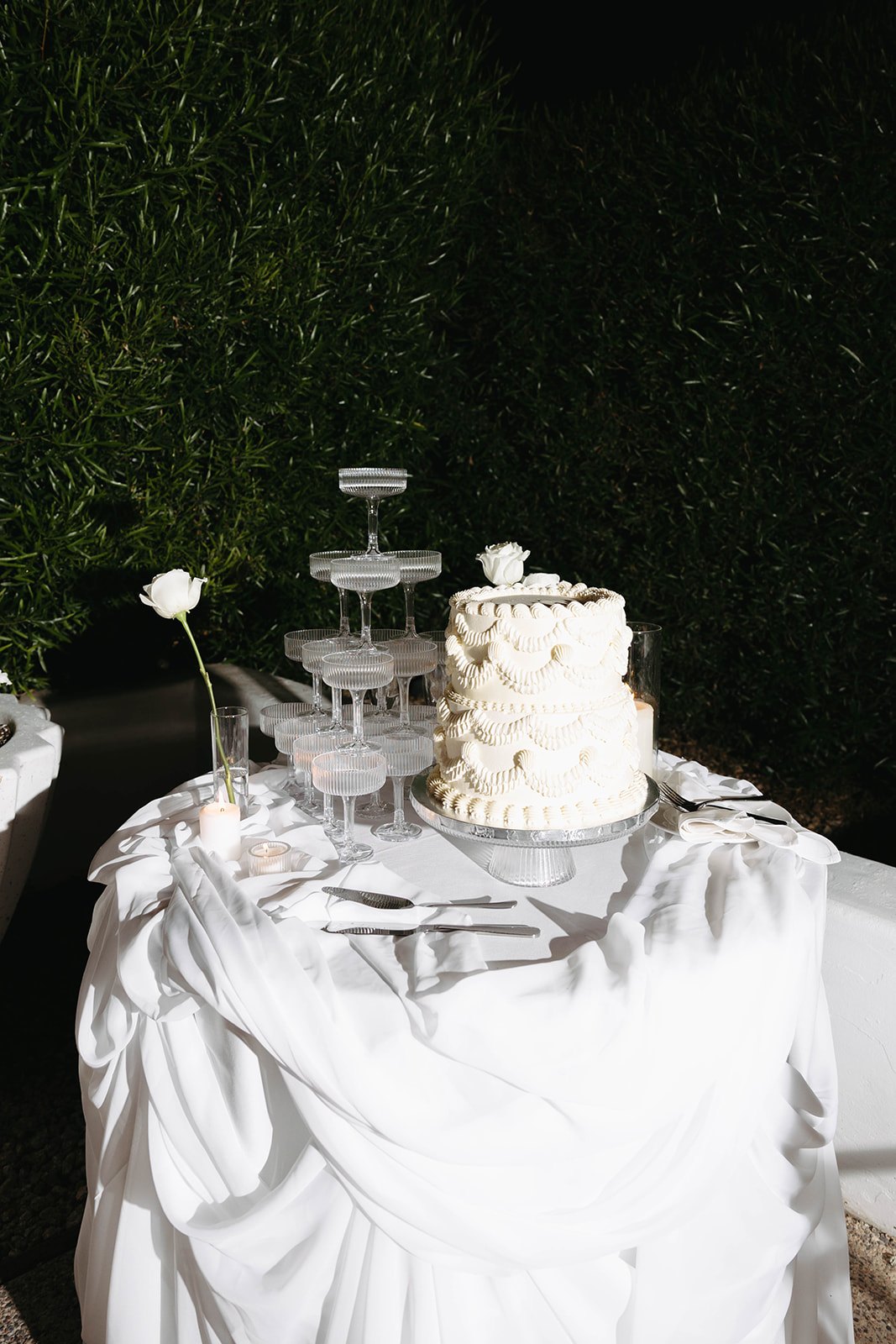 The vintage piped wedding cake beside the coupe tower by candlelight