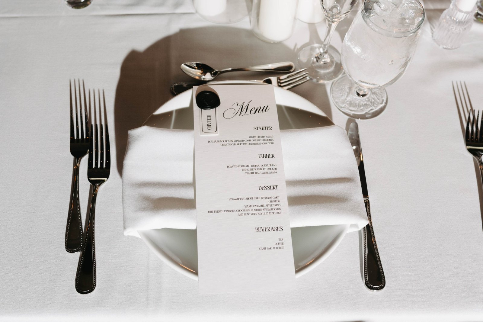 A wax-sealed menu and name card folded into the napkin at each place
