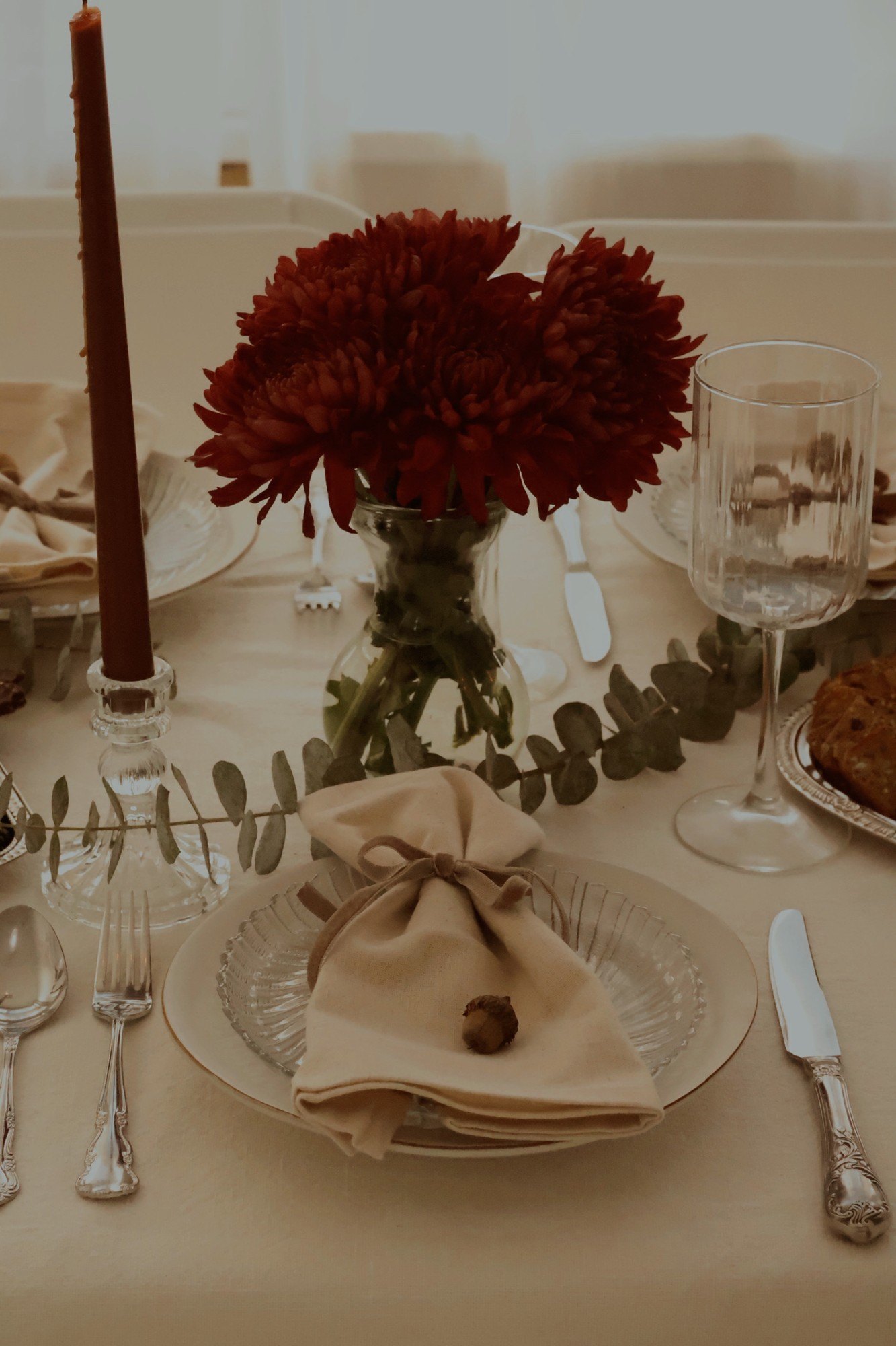 A place setting with velvet-tied napkin, acorn and burgundy mums