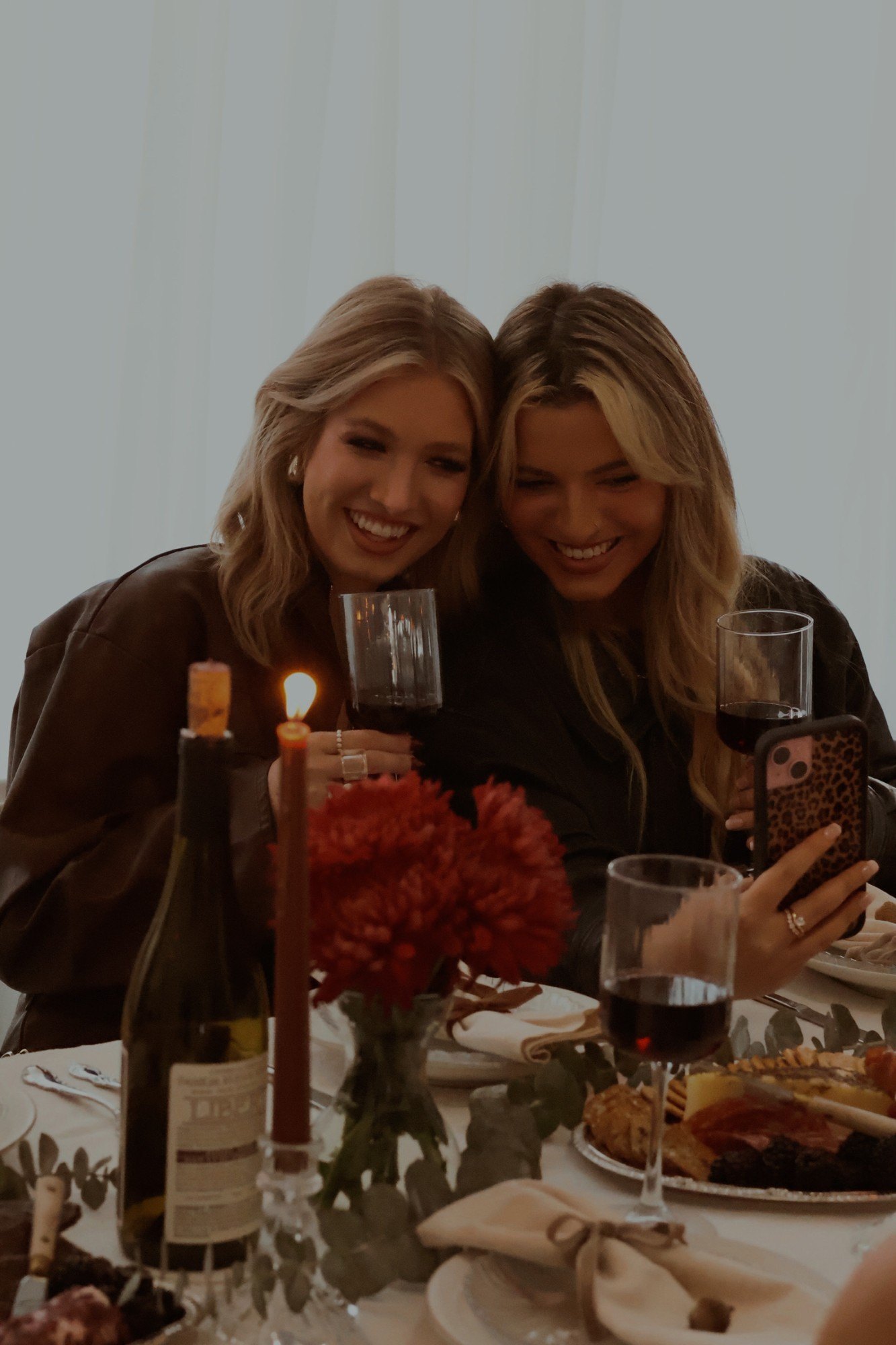 Two friends share a selfie over red wine and candlelight