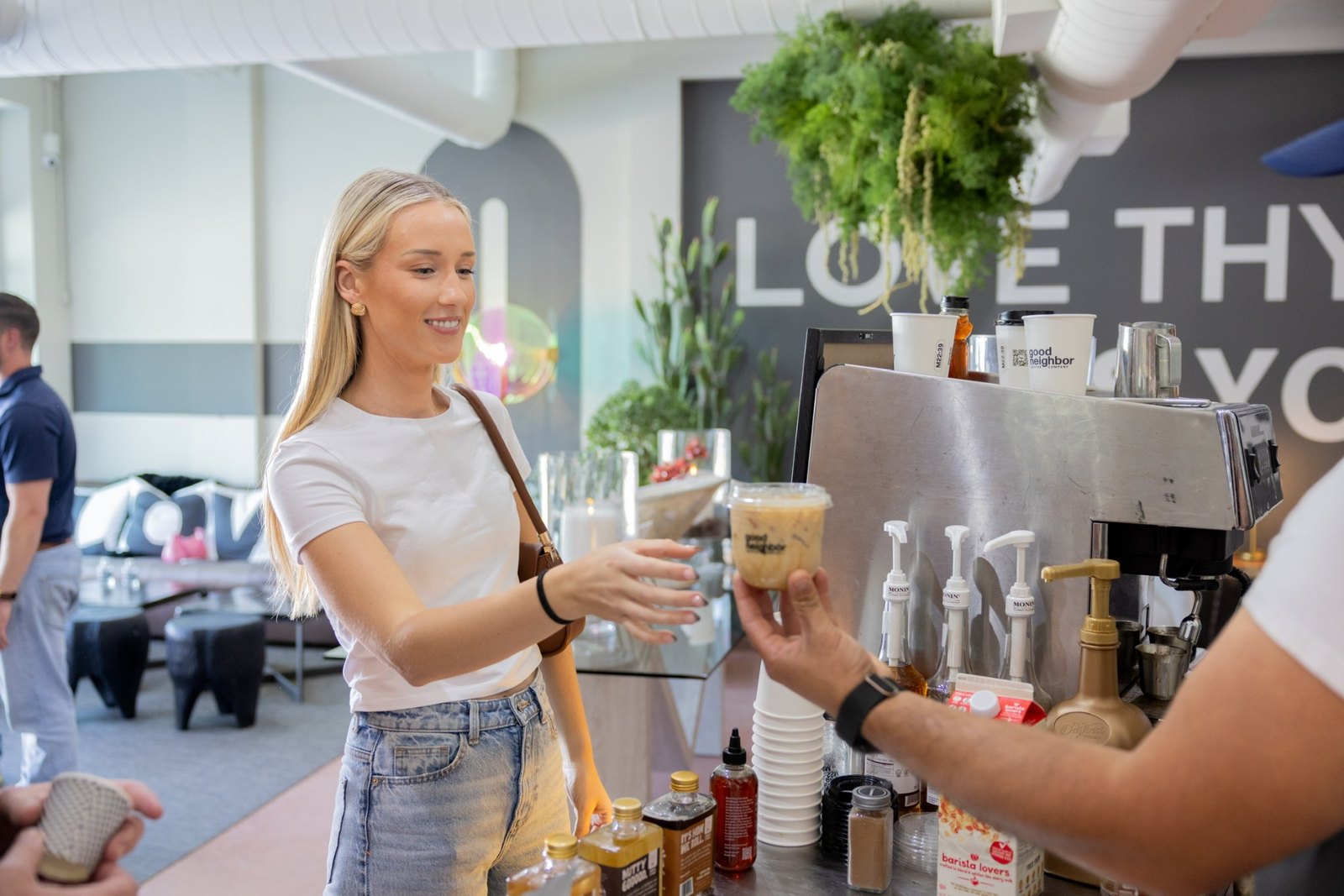 A barista hands an iced coffee across the Good Neighbor espresso bar
