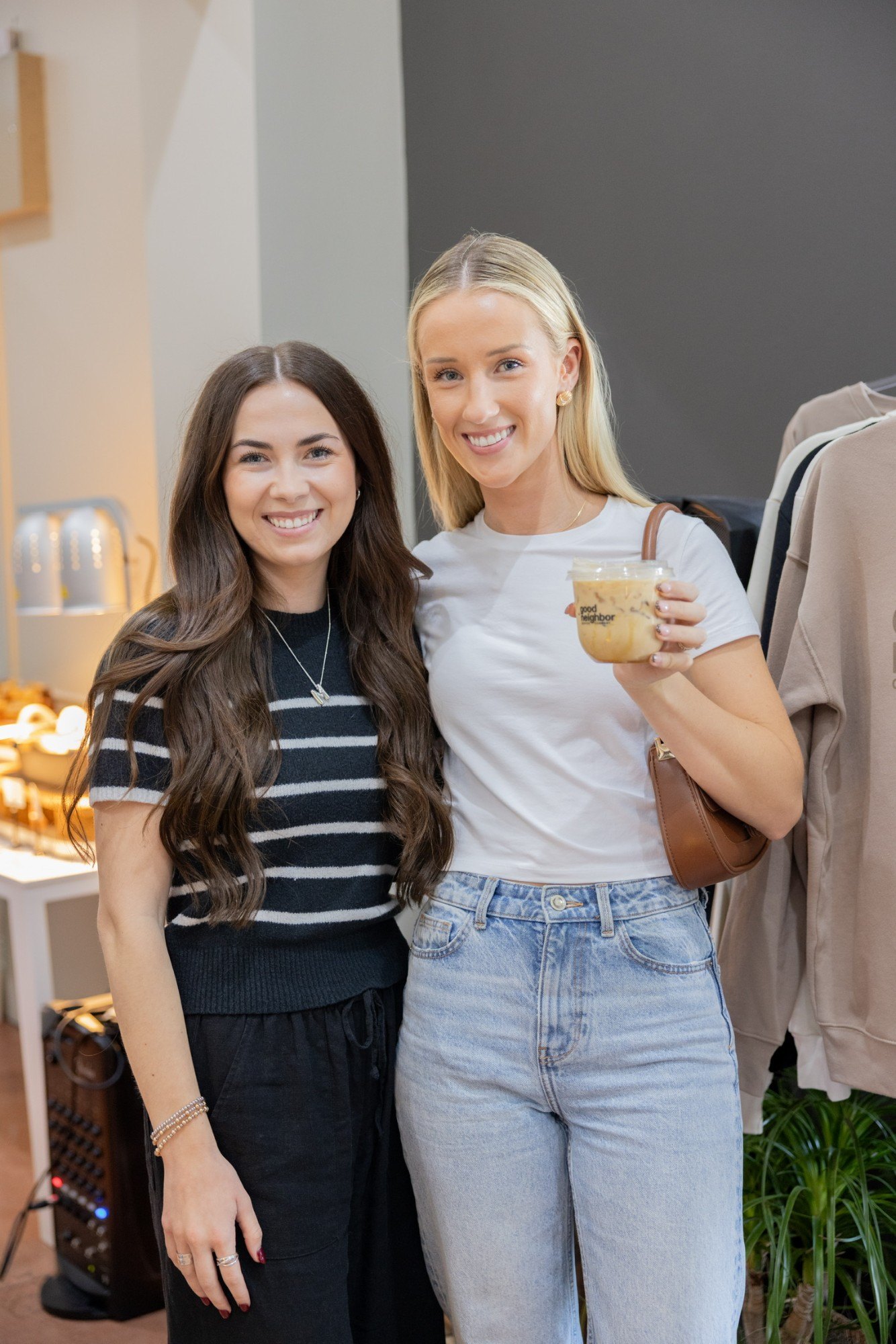 Two guests smiling with a Good Neighbor iced coffee