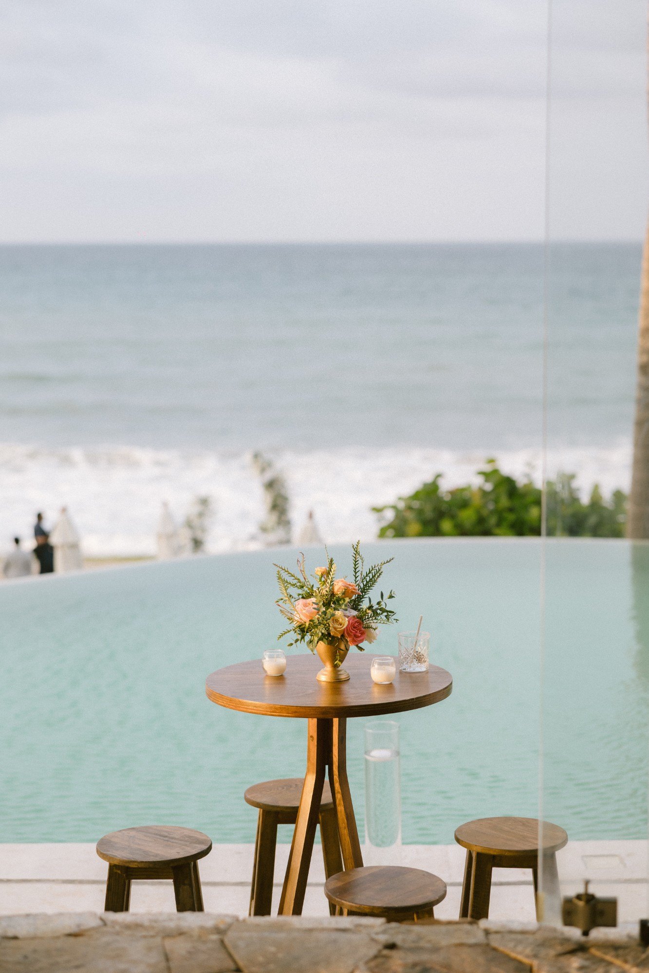 A cocktail table with roses beside the infinity pool overlooking the ocean