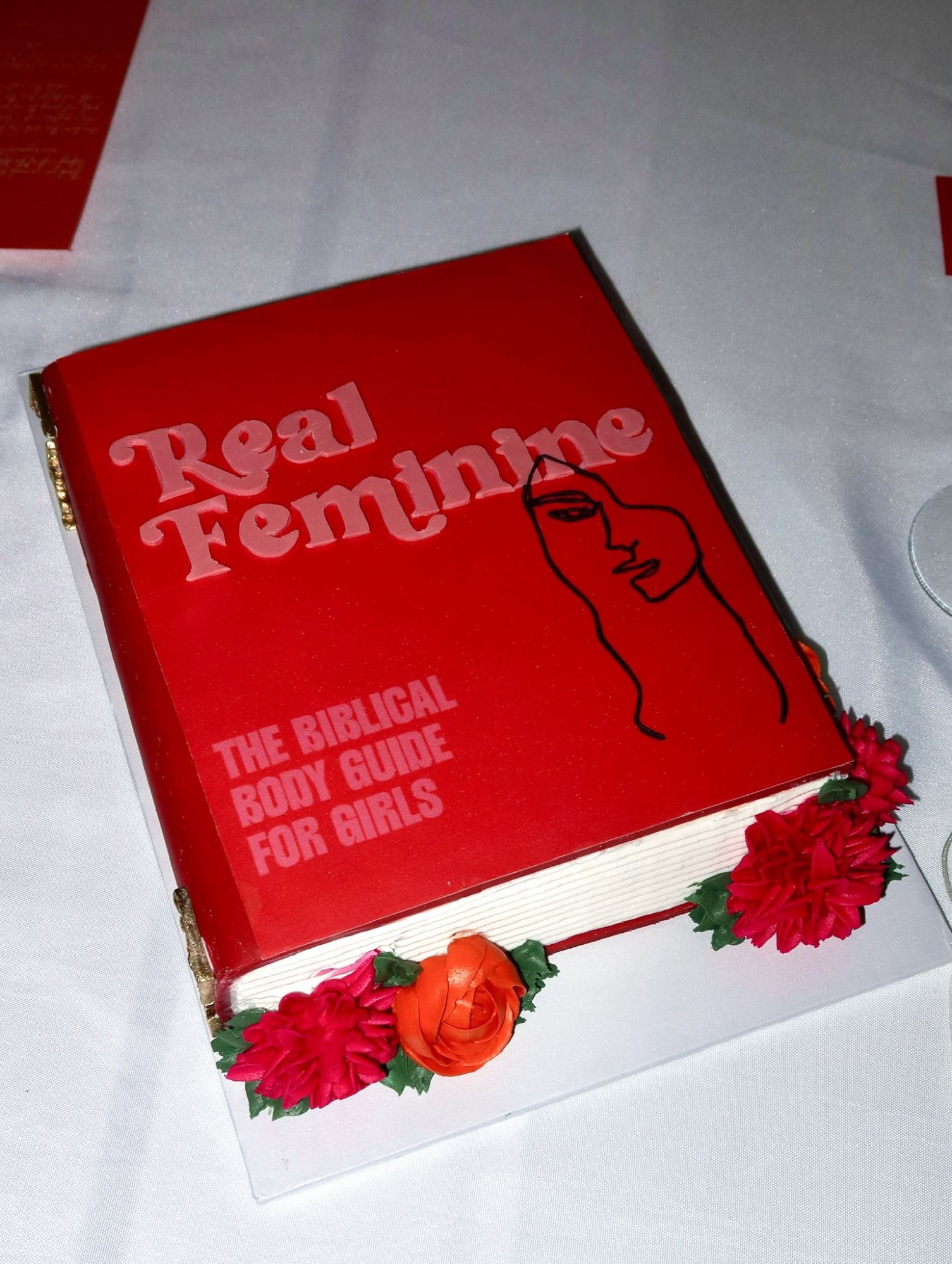 A cake styled as the Real Feminine book cover with buttercream florals