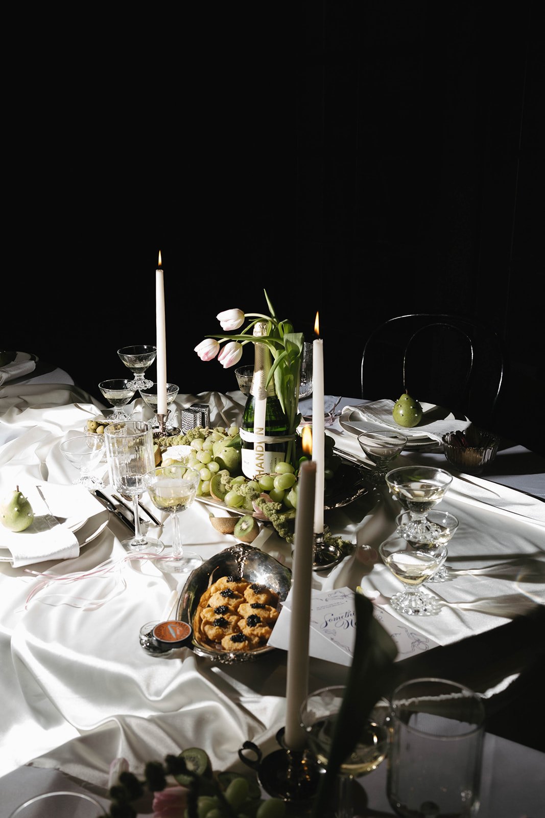 Tulips, champagne and caviar puffs styled across the satin-draped table
