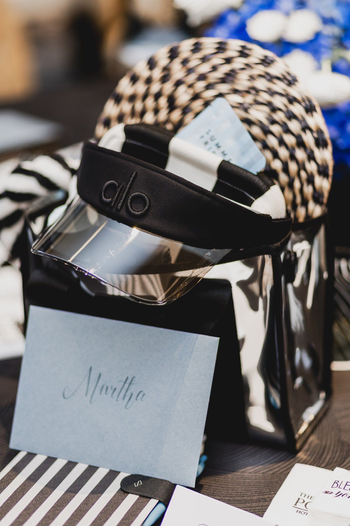 A calligraphed envelope with a visor and checkered gift bag at each seat