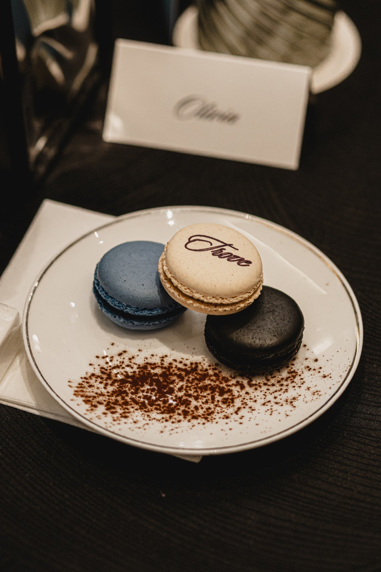 Trove script macarons in blue, cream and black on a gold-rimmed plate